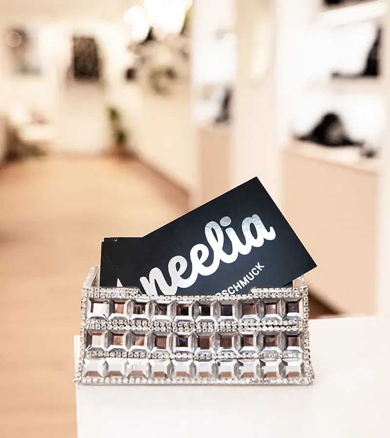 Visitenkarten von neelia Silberschmuck in einem Kartenhalter auf der Ladentheke
